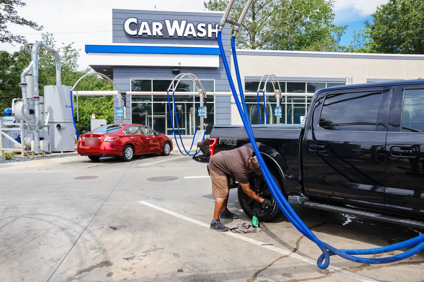 A man wiping down a truck tire at the free vacuums in front of the Zoom Express building